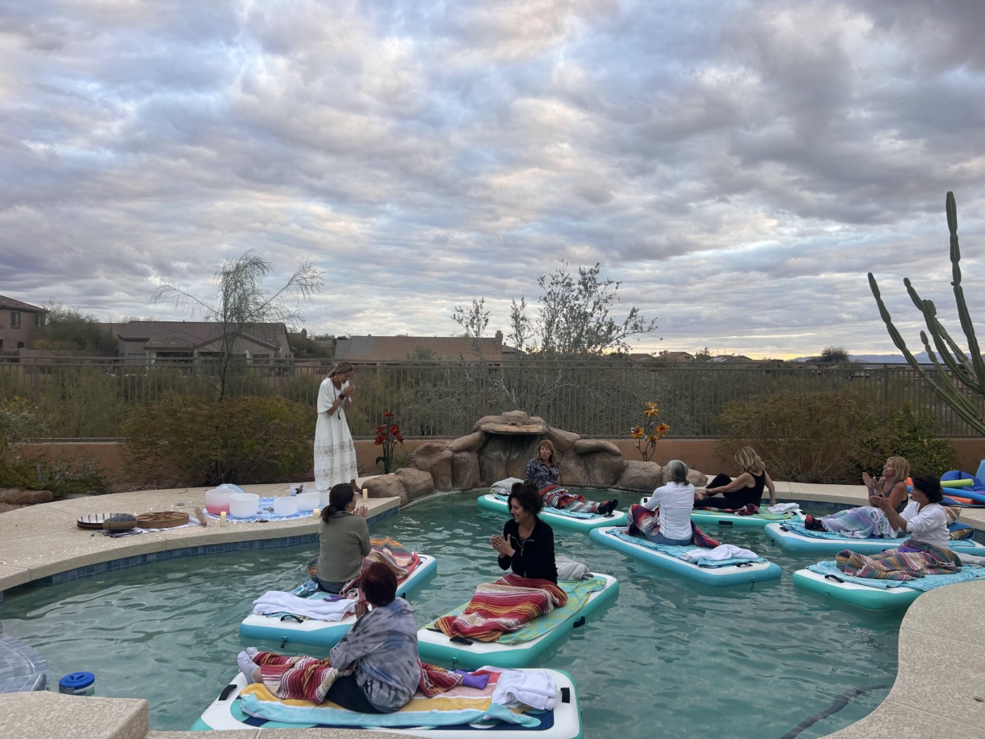 A bachelorette group floating on paddleboards at a backyard-pool soundbath